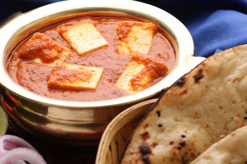 Paneer Butter Masala or Cheese Cottage Curry in serving a bowl or pan, served with naan or tandoori roti
