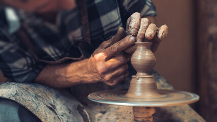 In the studio ceramics. Beautiful hand of an artisan over a potter's wheel. Traditional pottery craft.