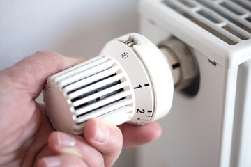 close-up of person turning thermostat on radiator to anti frost protection