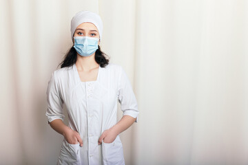 Nurse young medic standing hands in pockets looking at the camera. Female doctor dressed in medical...