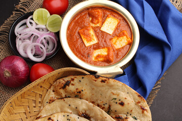 Paneer Butter Masala or Cheese Cottage Curry in serving a bowl or pan, served with naan or tandoori roti
