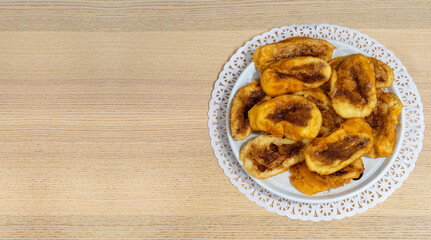 Top view of a plate full of torrijas (french toast) a typical spanish dish for holy week. Soaking bread in milk and egg and fried with cinnamon and sugar toppings. Sweet dessert on wood table.