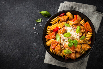 Pasta chicken with vegetables on black table.