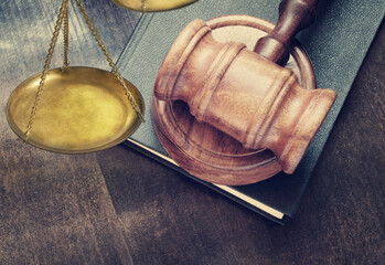 Wooden gavel on legal book and scale close up, justice and law concept