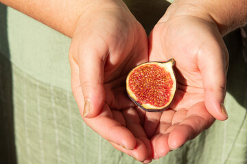 Half a fig is in the hands of a woman. Harvesting. Selective focus.