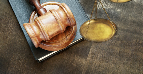 Wooden gavel on legal book and scale close up, justice and law concept