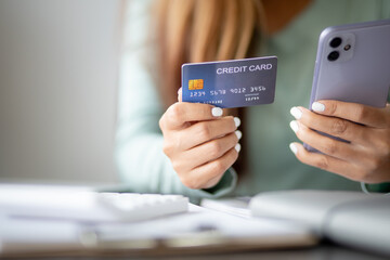 Close up woman hand using credit card and smartphone laptop for buying online shopping