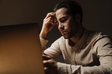 Serious pensive brunette businessman working on laptop