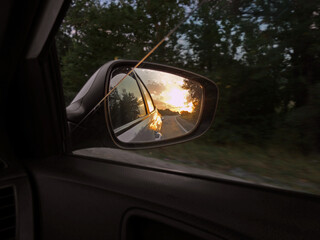 sunset and road in the rearview mirror