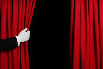Person opening red front curtains on black background, closeup. Space for text