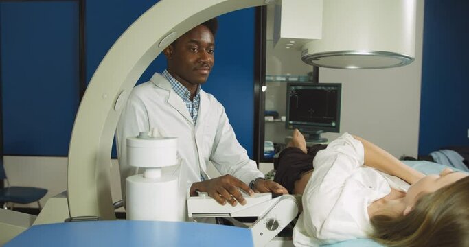 Lithotripsy for kidney and ureteral stones in modern center. Professional African man doctor, using ultrasound scan to determine the stone position before the lithotripsy for his female patient