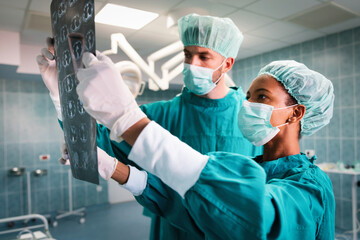 Professional medical team with doctors and surgeon examining patient's x-ray image