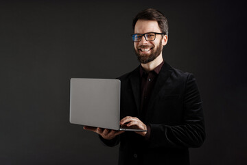 Bearded happy man in jacket smiling while using laptop