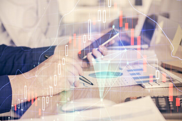 Double exposure of man's hands holding and using a digital device and forex graph drawing. Financial market concept.