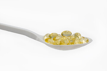 cod liver oil capsules on spoon, white background