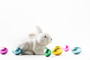 Macro shot of white rabbit among coloful eggs on the white background. Easter background