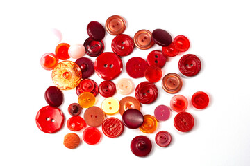 Colorful red and pink buttons on a white background. Lots of red buttons. Old vintage buttons close up. Copy space. Top view. Background of buttons. Flat lay.