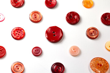 Colorful red and pink buttons on a white background. Set of red buttons. Old vintage buttons close up. Copy space. Top view. Background of buttons.