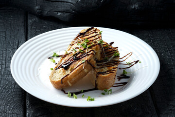 sandwich, bruschetta, toast, breakfast, croutons in sauce with herbs on a plate, on black wood