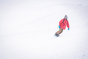 Front side view male person isolated snowboarding downhill in snowy conditions. Filming action camera winter adventures concept.