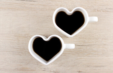 Two mugs in the shape of a heart with black coffee