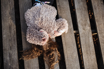 Portrait of a happy little girl lying on a wooden background. Beautiful baby enjoys a walk in the park. Fashionable children.