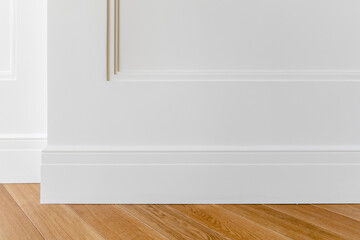 Fragment of classic white interior with wooden french herringbone parquet floor and installed wall...
