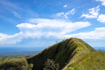Green mountain path under blue sky optimistic landscape. Rural land scenery. Summer travel hiking in green hills. Untouched nature parkland. Volcanic island relief. Trail in mountains