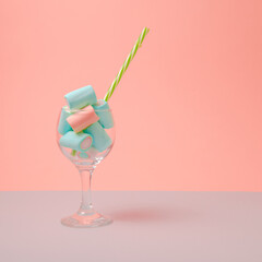 Blue marshmalow drink with green straw. Pink background.