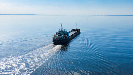 Obraz premium A large sea vessel goes by the sea in sunny calm weather, aerial view