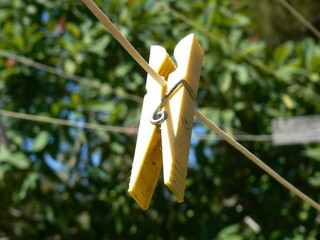 Focus sur une épingle à linge jaune clair accroché sur une corde blanche, en plein air