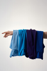 Colorful basic T-shirts on female hand against grey background