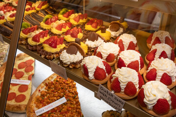 Fresh delicious sweet cakes with strawberries are in the store behind a glass window