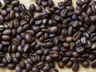 Coffee flavored freshly roasted beans are scattered on the wooden table