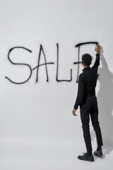 Rear view of young boy writing inscription sale on wall