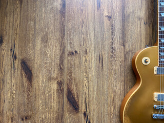 gold electric guitar made from a genuine mahogany Popular musician on veneer brown wood background with copy space on right for letter. business and music concept. Wallpaper or background. top view.