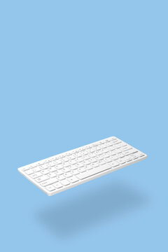 . The white keyboard levitates against a blue background, the shadow is clearly visible. Studio photography. Concept for online work, training, commerce, web design. Empty space for text.