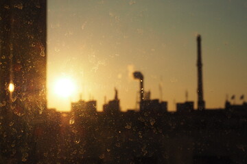 Pomarańczowy zachód słońca nad miastem wśród dachów - obrazy, fototapety, plakaty