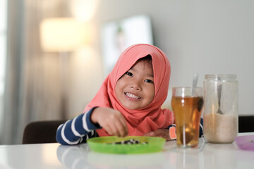 smiling muslim girl are having breakfast dessert at home