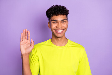 Photo of young cheerful afro man happy positive smile wave hand hello hi isolated over violet color background © deagreez