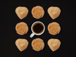 Creative composition of fresh baked muffins with cup of coffee on black wood background, heart and rose shape, food concept, flat lay, top view