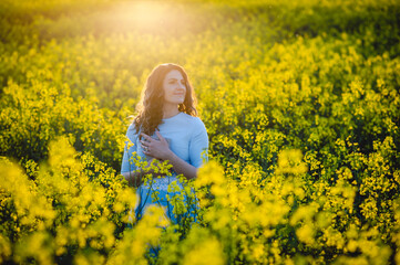 Happy girl hugs the bible in the sunlight on a background of yellow flowers. Girl with a book outdoors. Concept for faith, spirituality and religion. Peace, hope