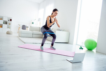 Full size photo of happy positive smiling beautiful girl exercising fit mat at home watching sportive video in laptop computer