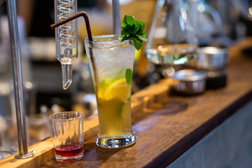 Close up the lemonade drink with ice in a clear glass beside a glass tube and the laboratory, adjust the flavor to the right, drink it, and refresh it, for sale in summer