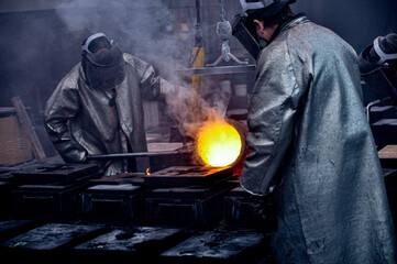 two people casting molten metal at a foundry