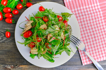 Fresh salad with fresh herbs, cherry tomatoes, soft Italian cheese on a plate. A delicious and healthy meal.