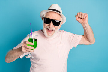 Photo of elderly man happy positive smile enjoy drink cocktails vacation isolated over blue color...