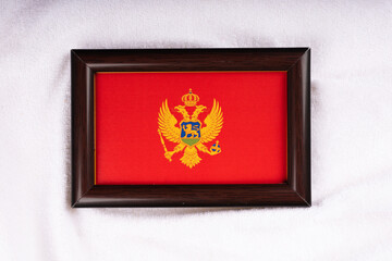Montenegro flag in a realistic frame on white cloth background flat lay photo