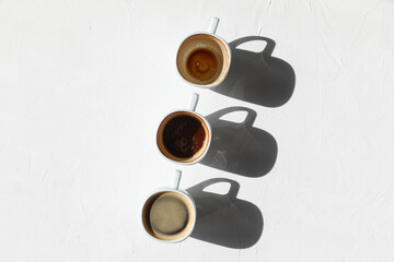 Making coffee - a cup of coffee with foam, and coffee beans  on the white table - top view