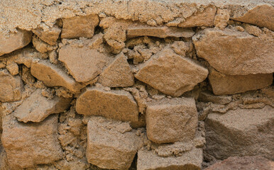 detail section of an dusty old broken stone wall, background texture, closeup of a dry crumbling stone wall